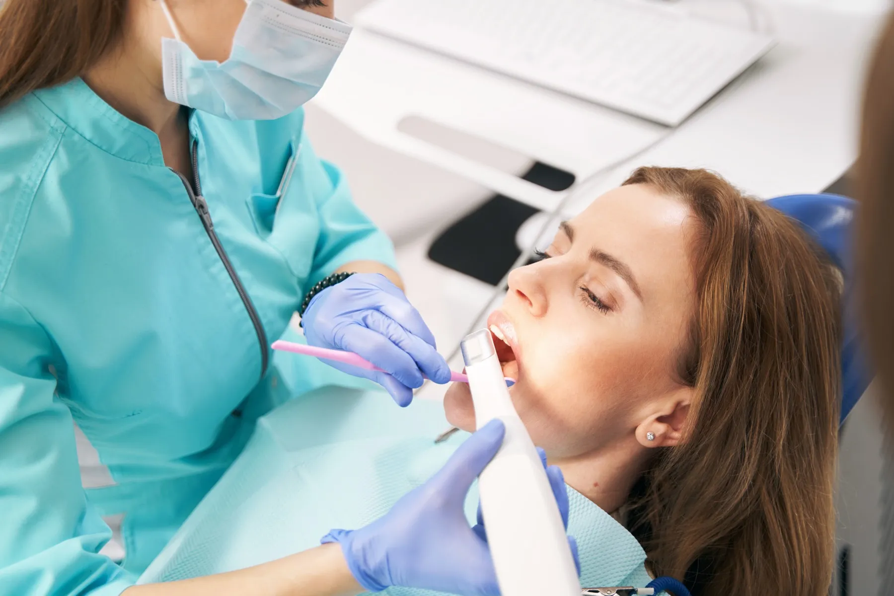 Dentist performing dental examination on patient in blue dental chair