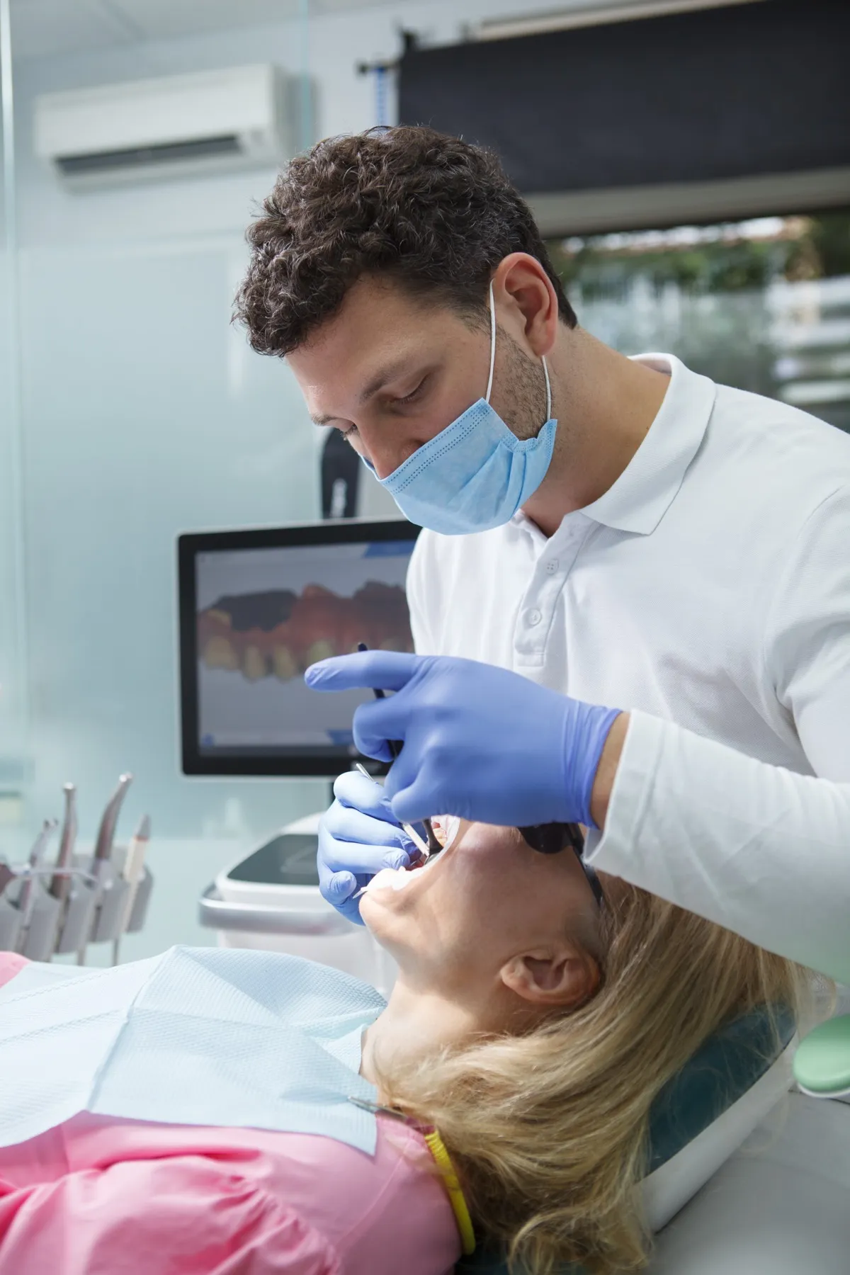 Dentist in blue gloves and mask treating patient in dental clinic