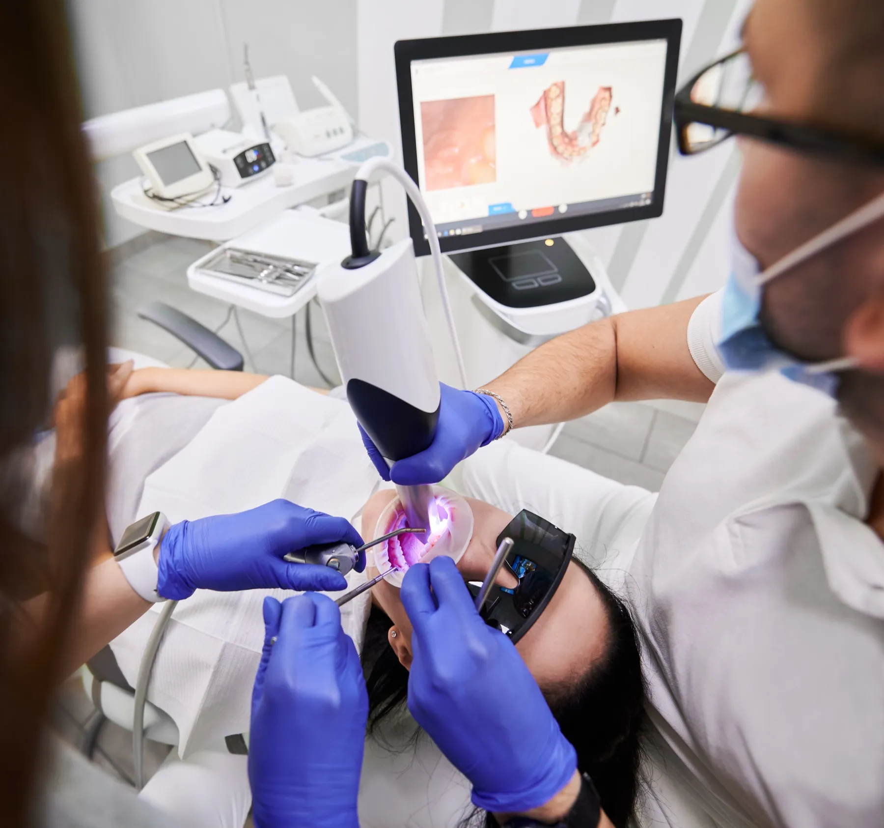 Dentist performing dental procedure with blue gloves and UV light