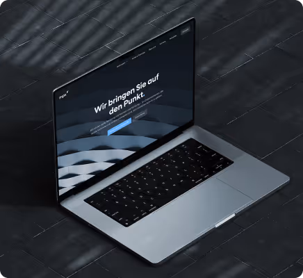 Offener Laptop auf dunklem Boden mit Webseite, die den Text ‚Wir bringen Sie auf den Punkt‘ zeigt.