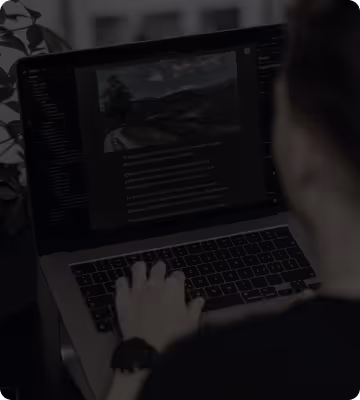 Person arbeitet an einem Laptop mit Bildbearbeitungssoftware, die ein Landschaftsbild und Text zeigt.