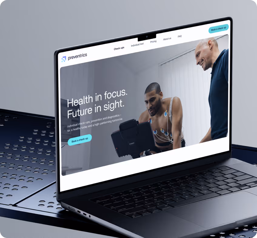Laptop zeigt Website von Preventrics mit Slogan 'Health in focus. Future in sight.' und Bild eines Mannes mit Elektroden am Oberkörper bei einem Gesundheitscheck.