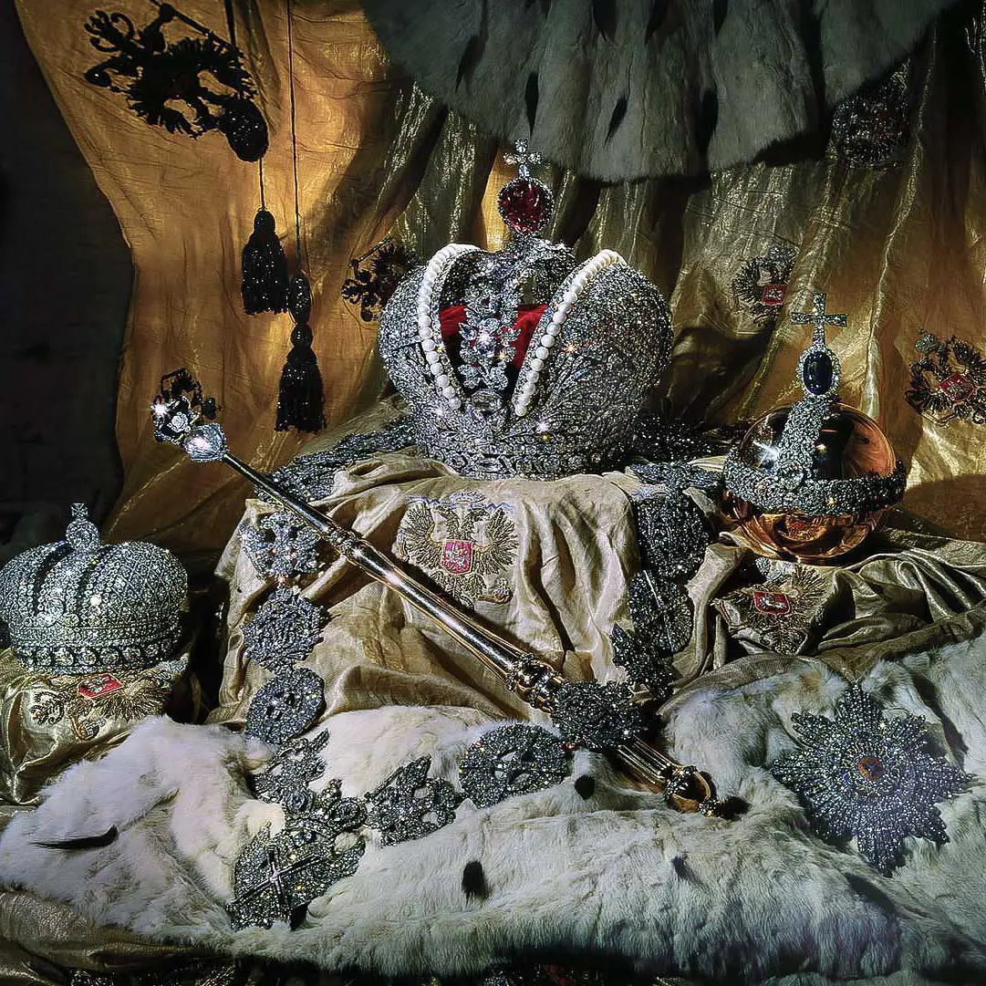 Regalias de Estado dos monarcas russos na exposição do Fundo de Diamantes sobre mantos de arminho e tecidos dourados com brasões bordados. Ao centro, destaca-se a Grande Coroa Imperial em estrutura rendada de prata incrustada de diamantes, ladeada por duas fileiras de pérolas e encimada por um espinélio vermelho-escuro com cruz. À esquerda repousa a Pequena Coroa Imperial, em diagonal apoia-se o cetro de ouro com o diamante Orlov, à direita surge a orbe de ouro coroada por uma safira azul, e em primeiro plano exibe-se o colar e a estrela de brilhantes da Ordem de Santo André.