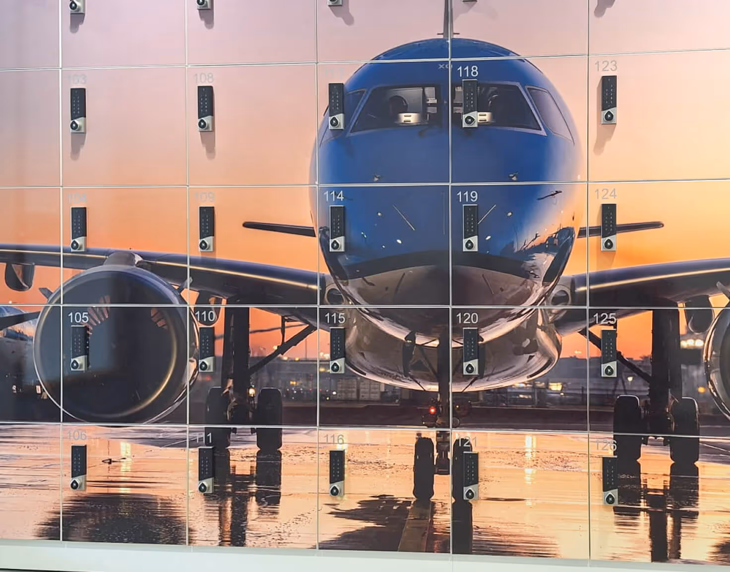Large image of an airplane nose and engines on a tarmac at sunset, divided into lockers with combination locks.