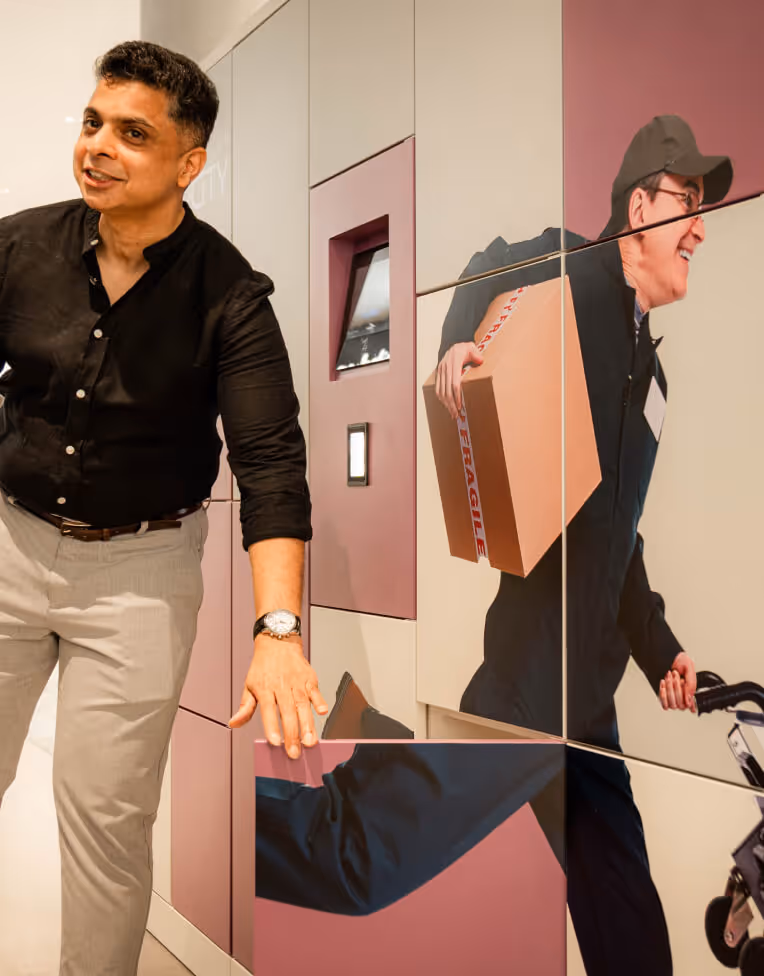 Man in black shirt and light pants interacting with a wall of cabinets featuring a large image of a delivery person carrying a fragile package and pushing a cart.