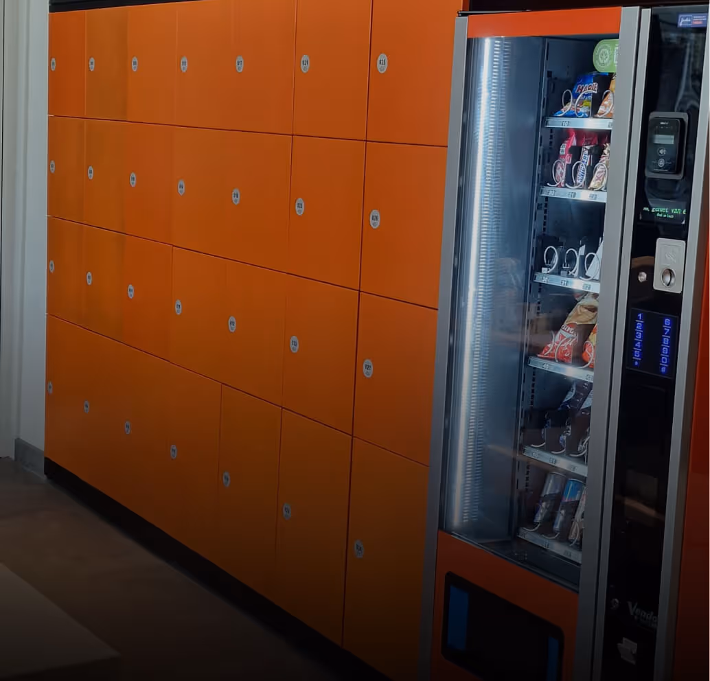 Orange parcel lockers labeled with numbers next to a vending machine stocked with snacks.