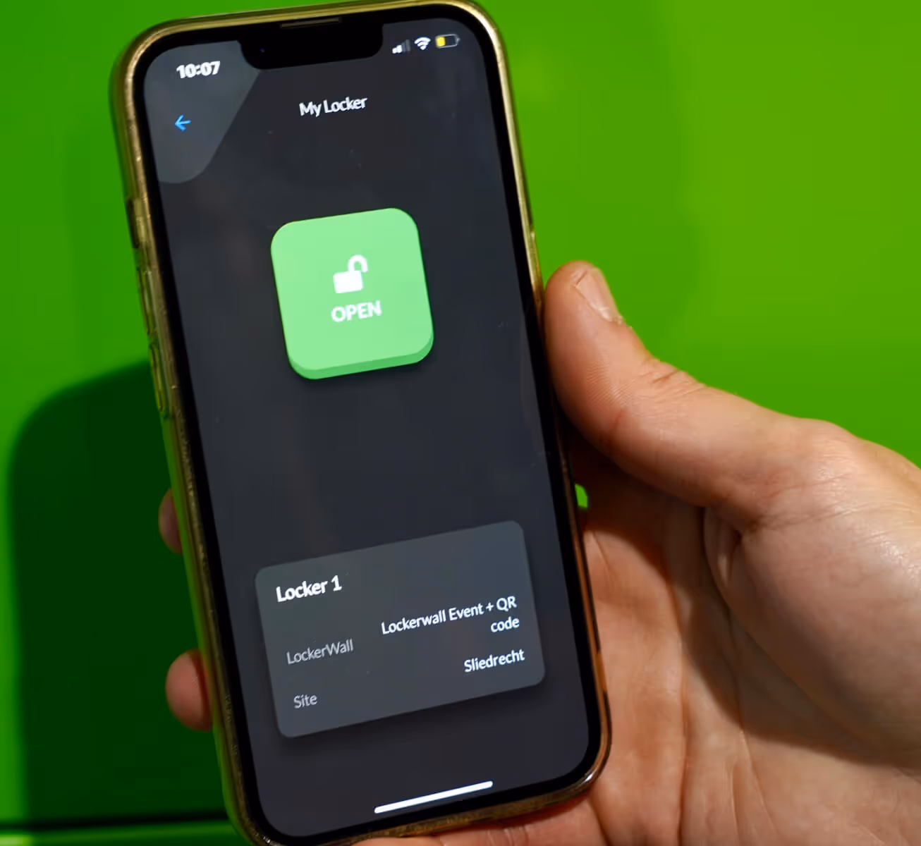 Hand holding smartphone displaying an app screen with a green unlocked padlock button labeled 'OPEN' and locker details below.