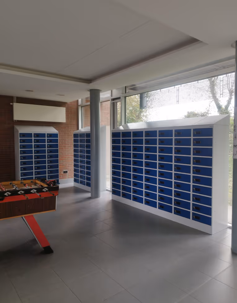 Room with multiple blue mailboxes along the walls and a foosball table in the foreground.