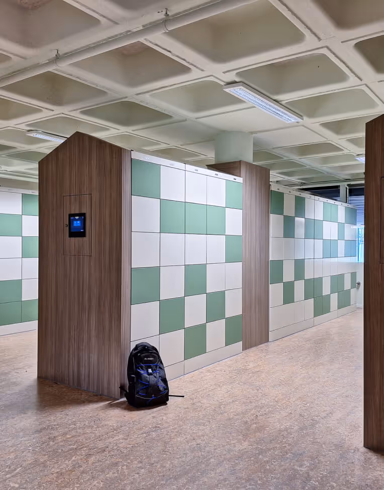 Modern locker area with green and white checkered lockers and a black backpack on the floor.