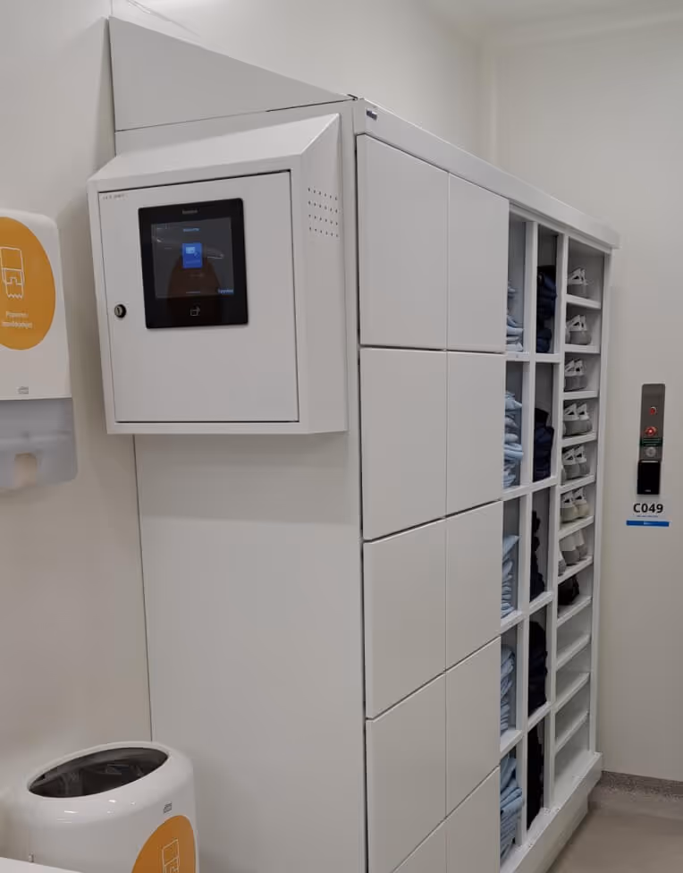 Automated storage locker system with multiple compartments, each holding folded clothes, in a clean, modern room.