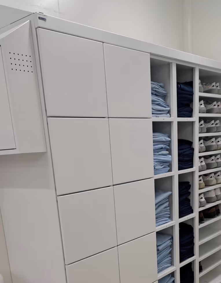 White cubby shelves with neatly folded blue and dark-colored clothes and white sneakers arranged on the right side.