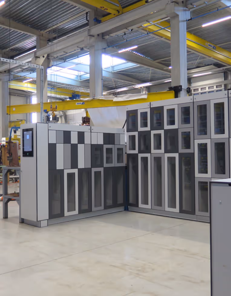 Industrial warehouse interior with large gray and white storage cabinets and yellow overhead cranes.
