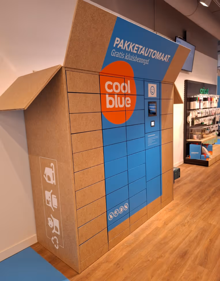 Cardboard package locker with blue panels and Coolblue logo in a modern indoor space.