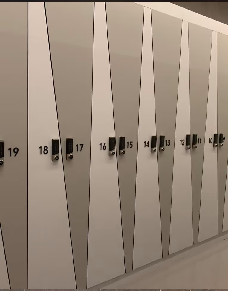 A row of modern lockers numbered 9 to 19 with alternating light and dark gray triangular panels and black combination locks.