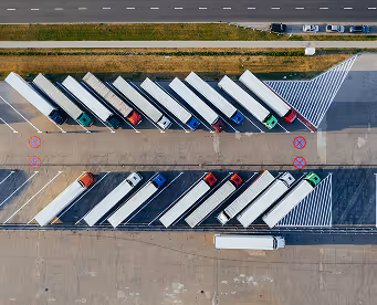 Aerial view of a parking lot with multiple trucks and trailers parked in two parallel rows.