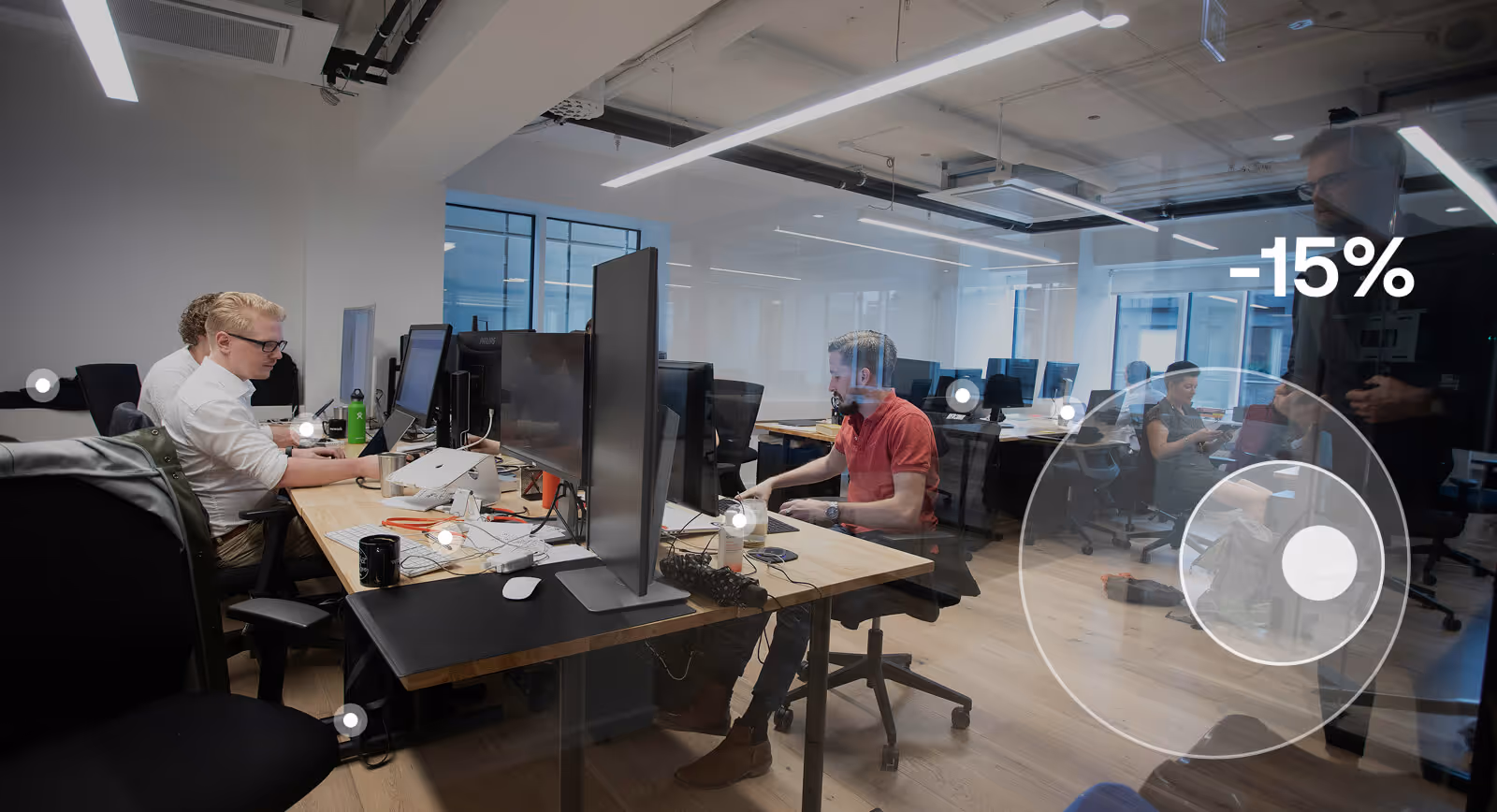 People working at desks with computers in a modern open office space.