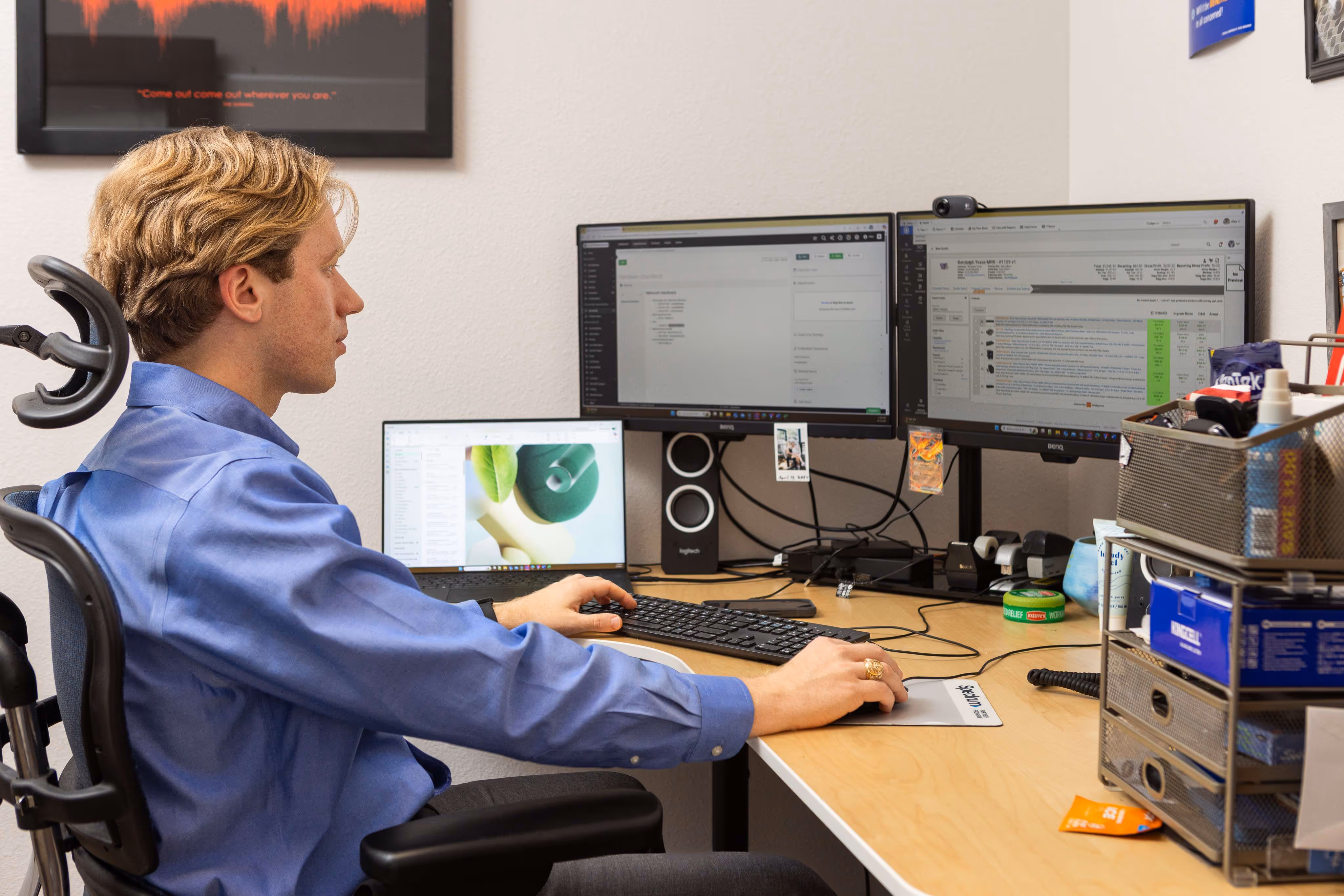 IT professional working at multi-monitor desk setup with keyboard and mouse in modern office workspace