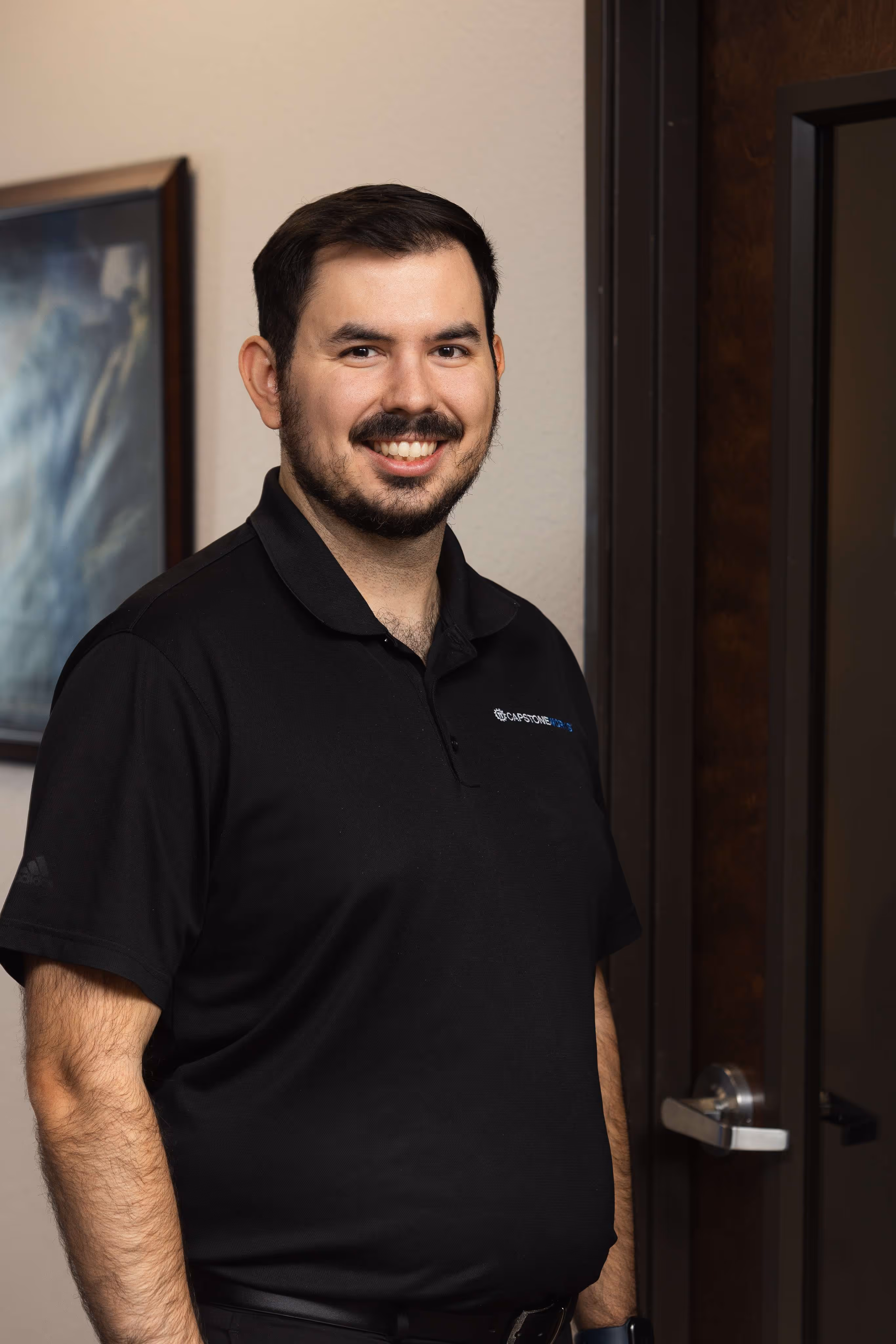 Capstone Works IT professional smiling in branded polo shirt at Austin managed services office