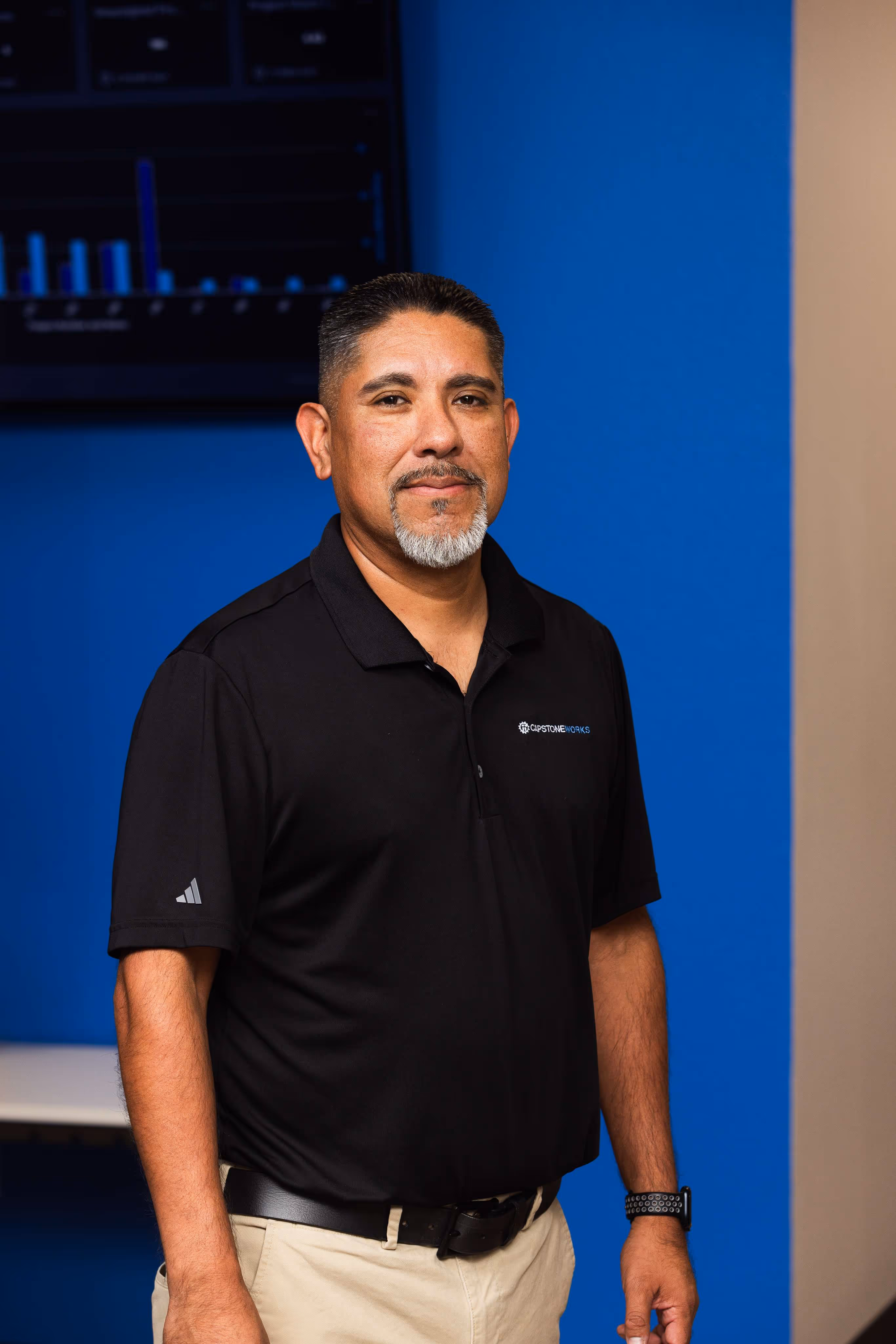 Capstone Works IT professional standing in modern Austin managed services office with data dashboard display