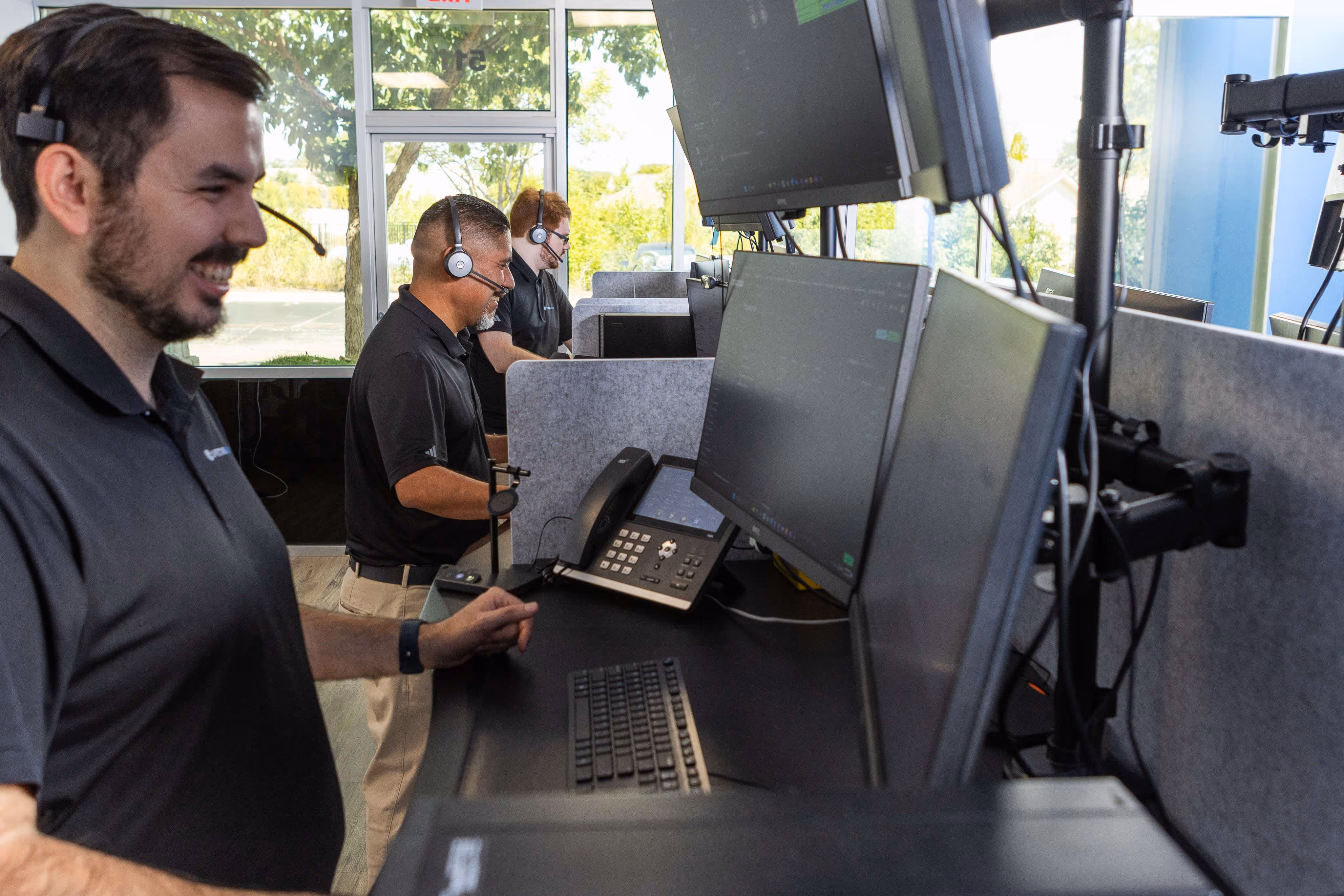 Capstone Works IT support technicians wearing headsets working at multi-monitor help desk workstations in Austin TX office