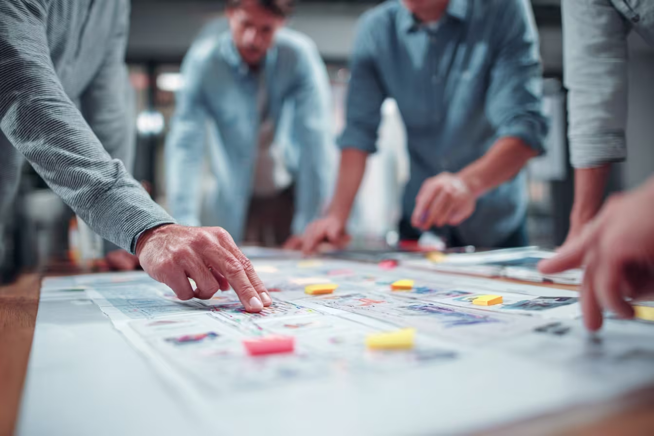 Team of IT professionals collaborating over printed network diagrams and project plans on a table in an Austin office