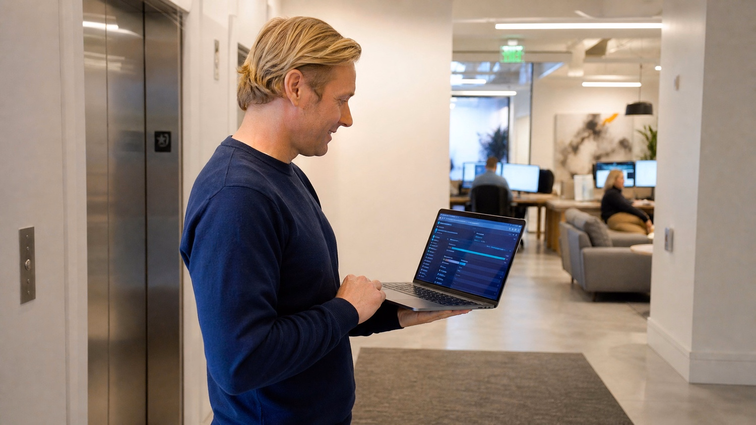 Man with laptop checks app deployment progress in lobby