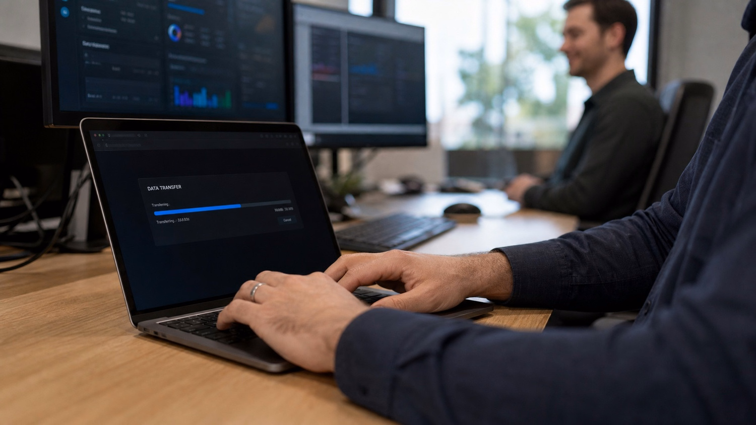 Mans hands typing on laptop, data transfer progress bar 67 chars