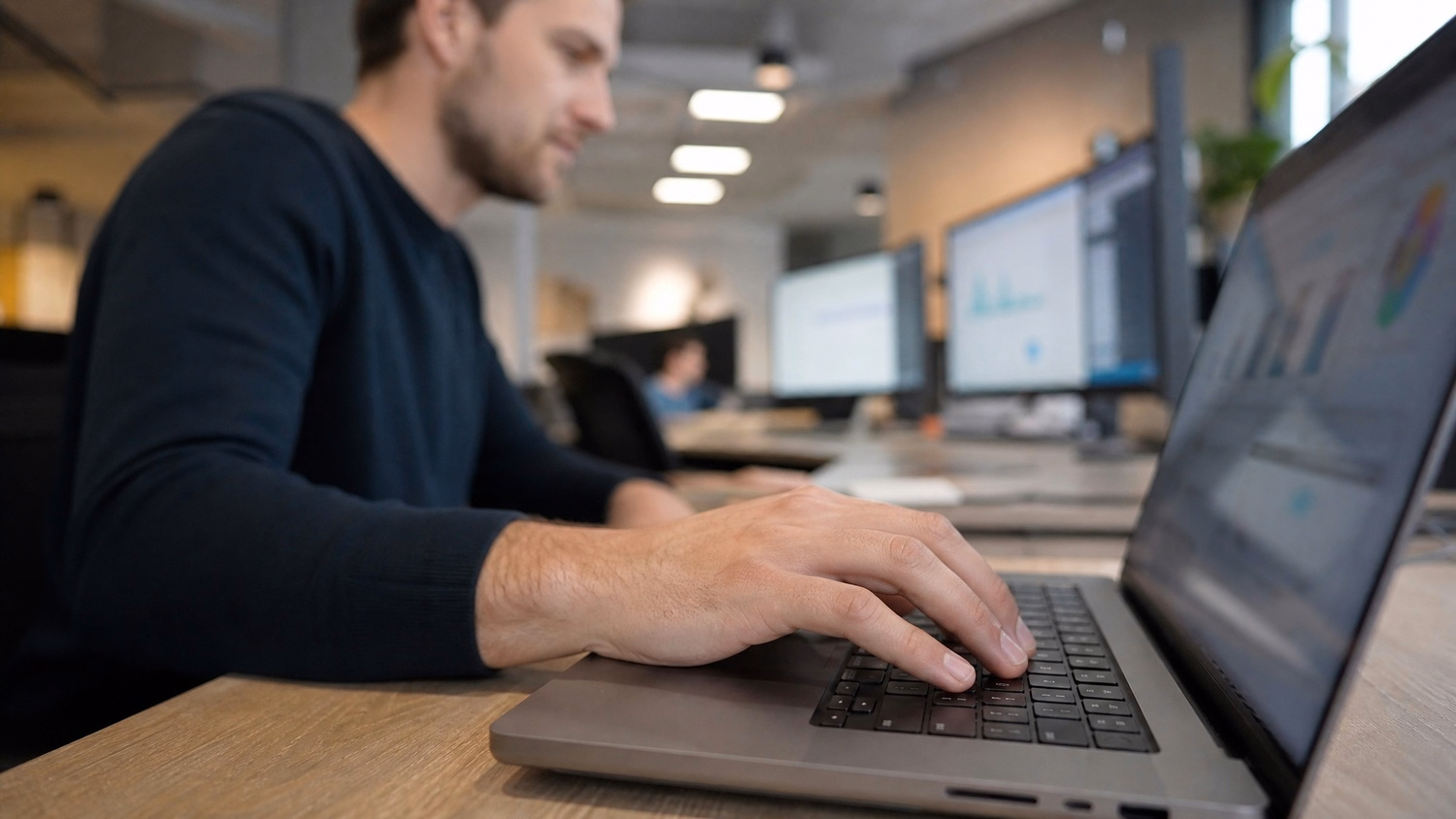 Hands typing quickly on laptop keyboard, RMM software screen blurred 77