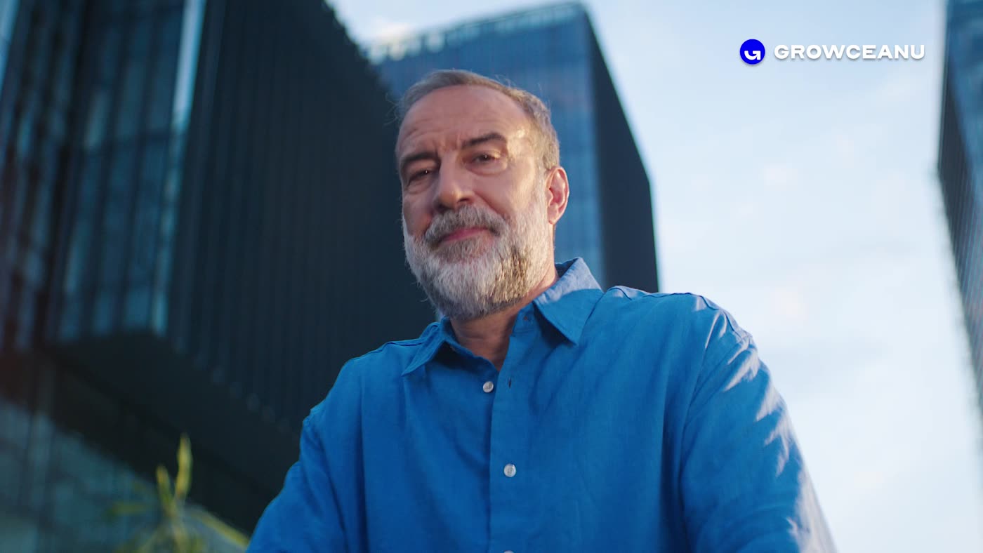Growceanu manifesto: a man in a blue shirt speaks in front of glass office buildings