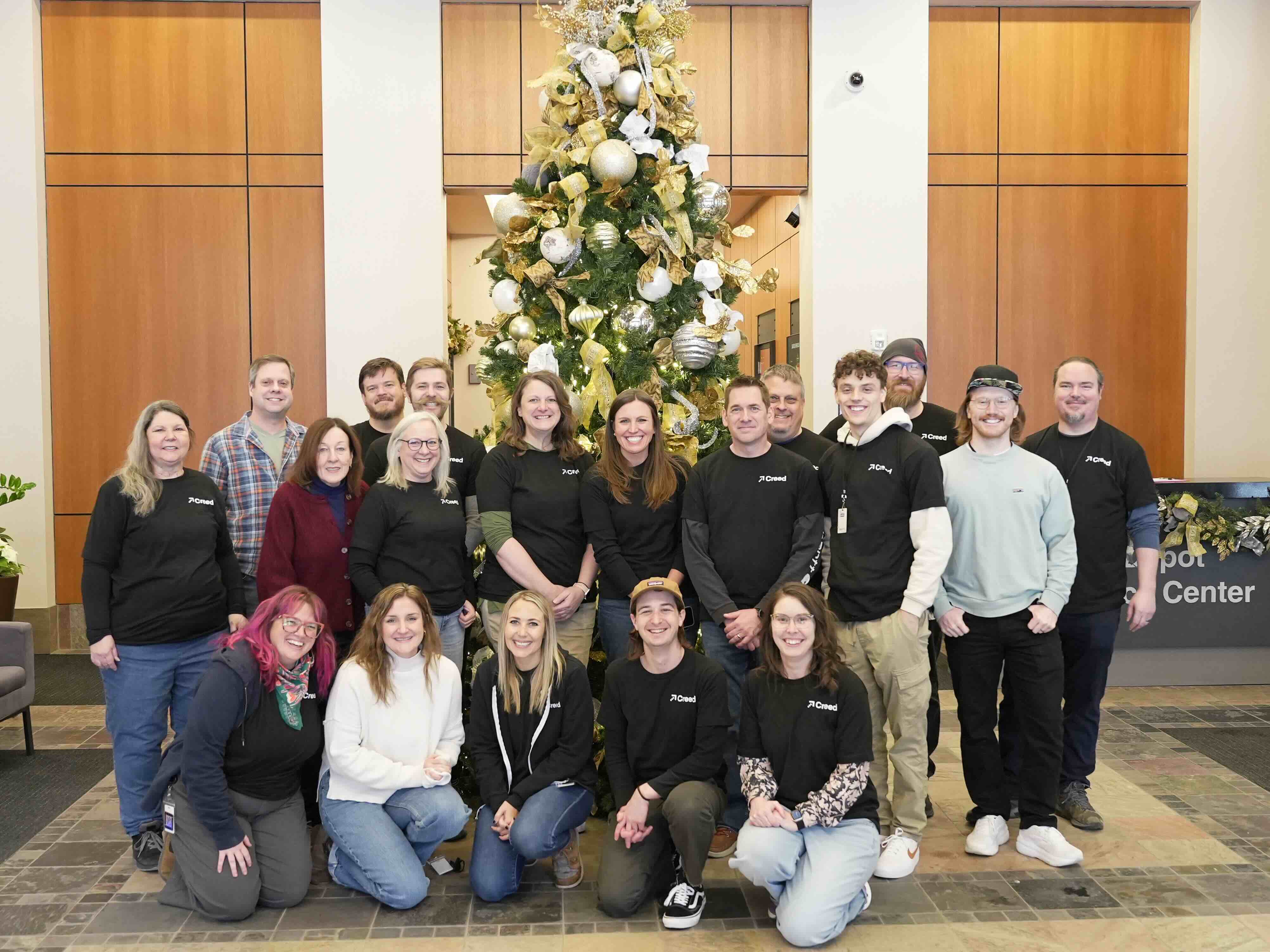 The Creed team standing in front of a Christmas tree decorated in white and gold decorations of bulbs, beads, and string. Everyone at Creed wishes the best to you and yours.