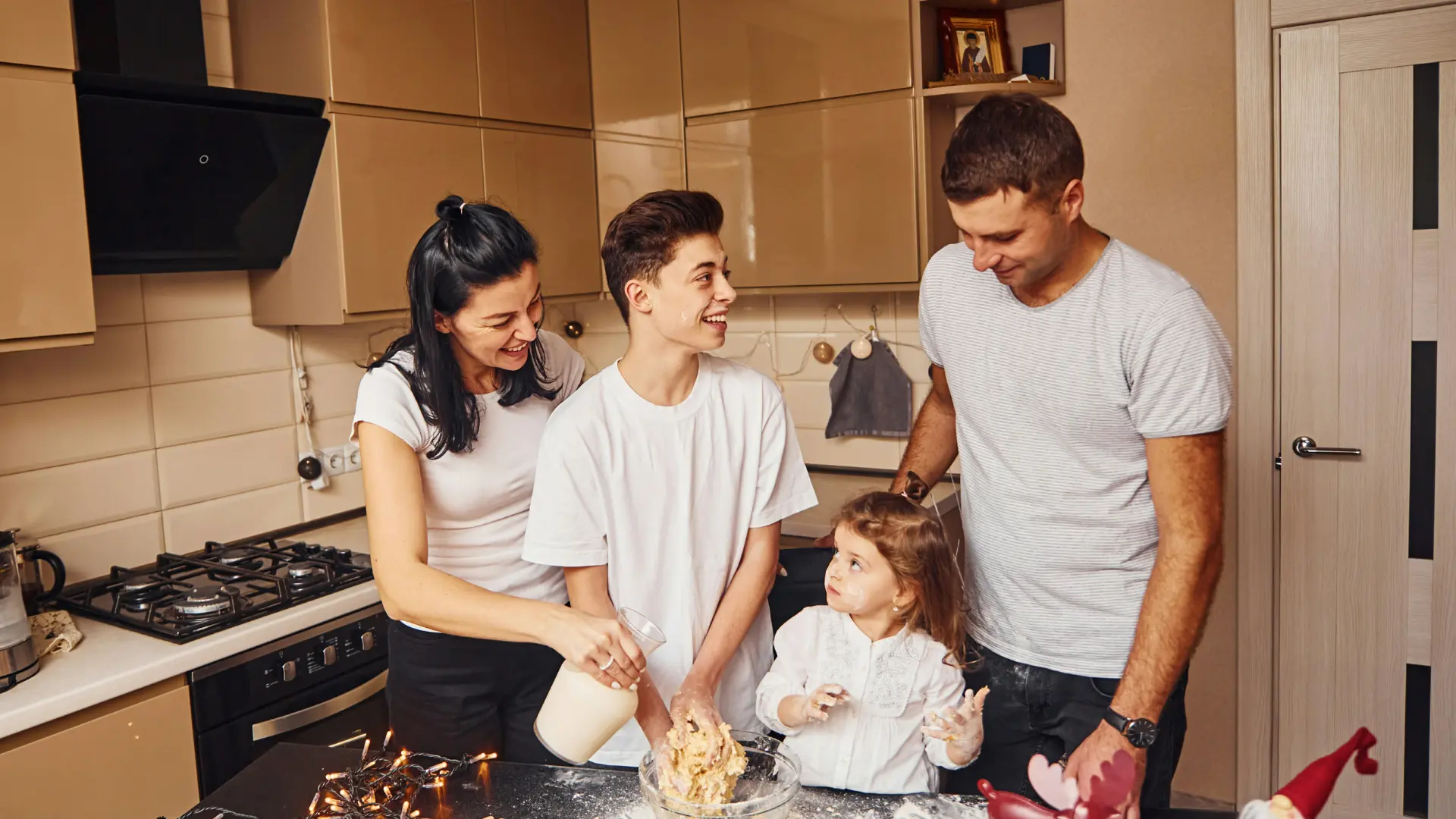 Famiglia in cucina mentre prepara l'impasto insieme, con sorrisi e gesti collaborativi.