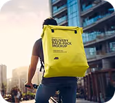 Person riding a bike in the city wearing a bright yellow delivery backpack.