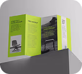 Green and white trifold brochure standing upright on a gray surface, featuring images of a laptop and a chair with text sections.