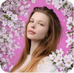 Young woman with long hair surrounded by white blossoms against a bright pink background.