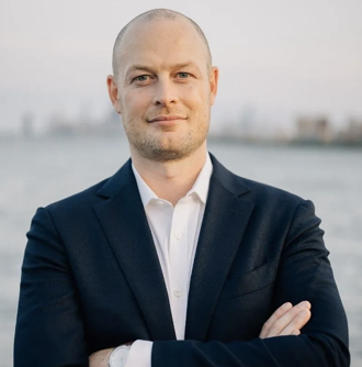 Joel Arnold, VP of Revenue Operations Strategy at Union Square Consulting, standing with arms crossed against a waterfront background.