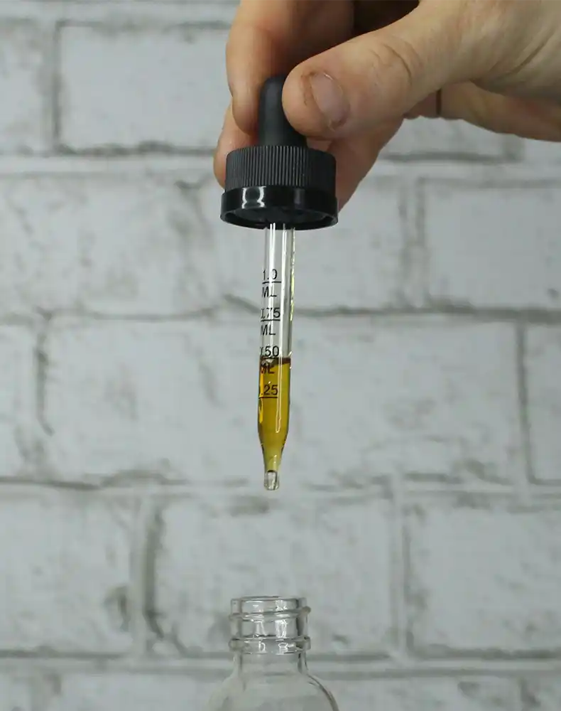 A CBD oil dropper being extracted from a bottle