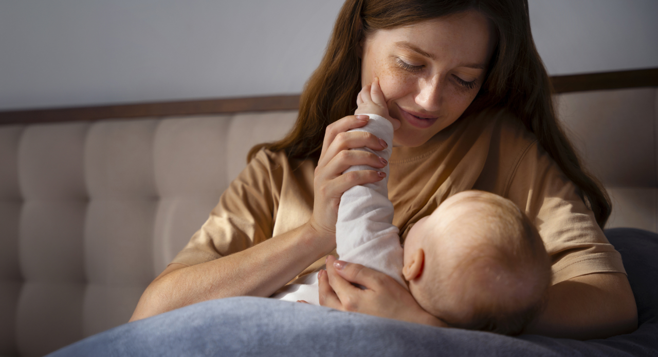 A mother gently holds her baby while looking down at it with affection.