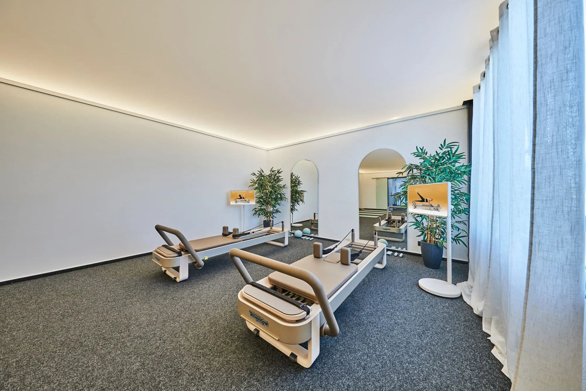 Technogym Reformer vor Vorhang und Spiegel im Sport Point Gießen, Bildschirm zeigt das Reformer-Pilates-Workout.