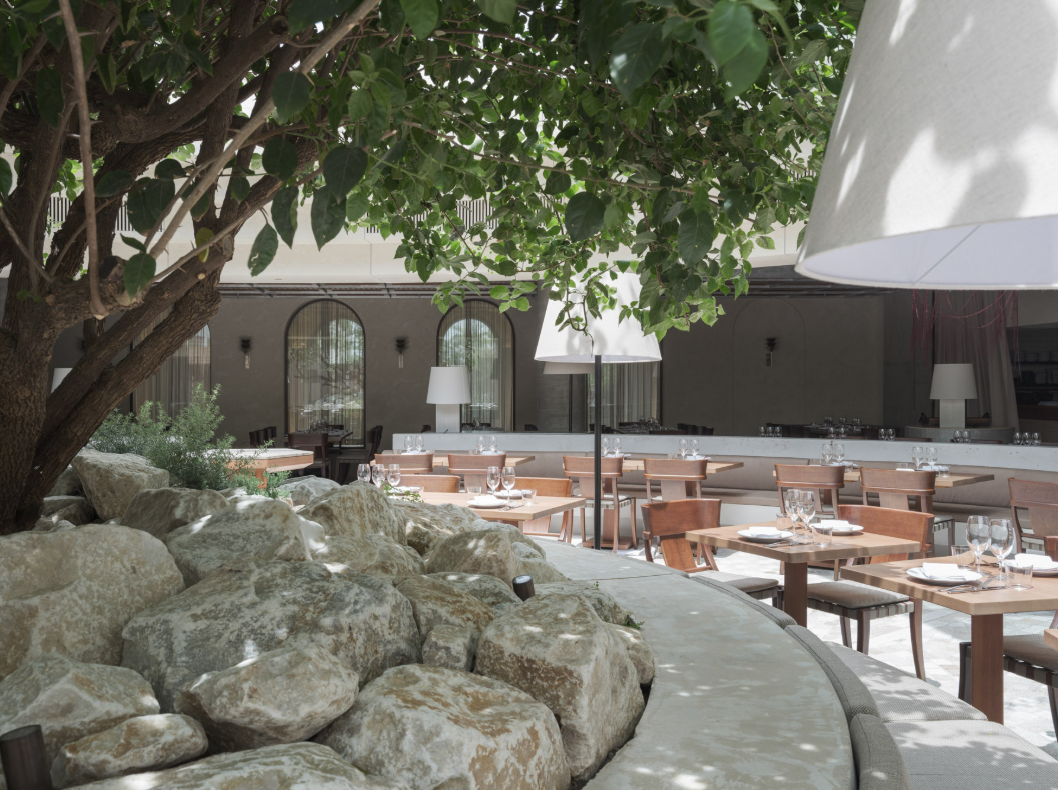 A large rock wall with tables and chairsAI-generated content may be incorrect.