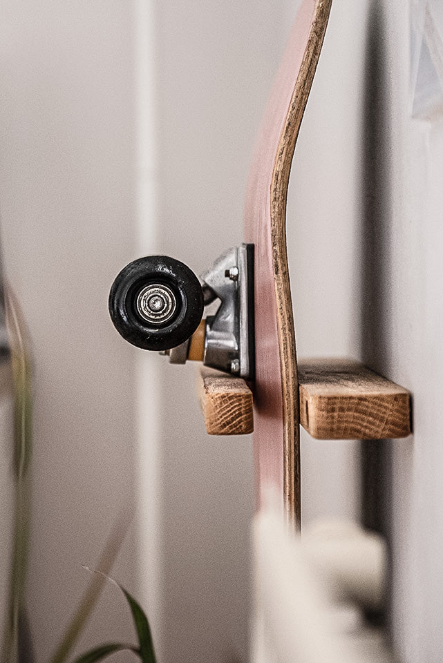 Vertical wall skateboard rack made of solid oak holding a skateboard securely