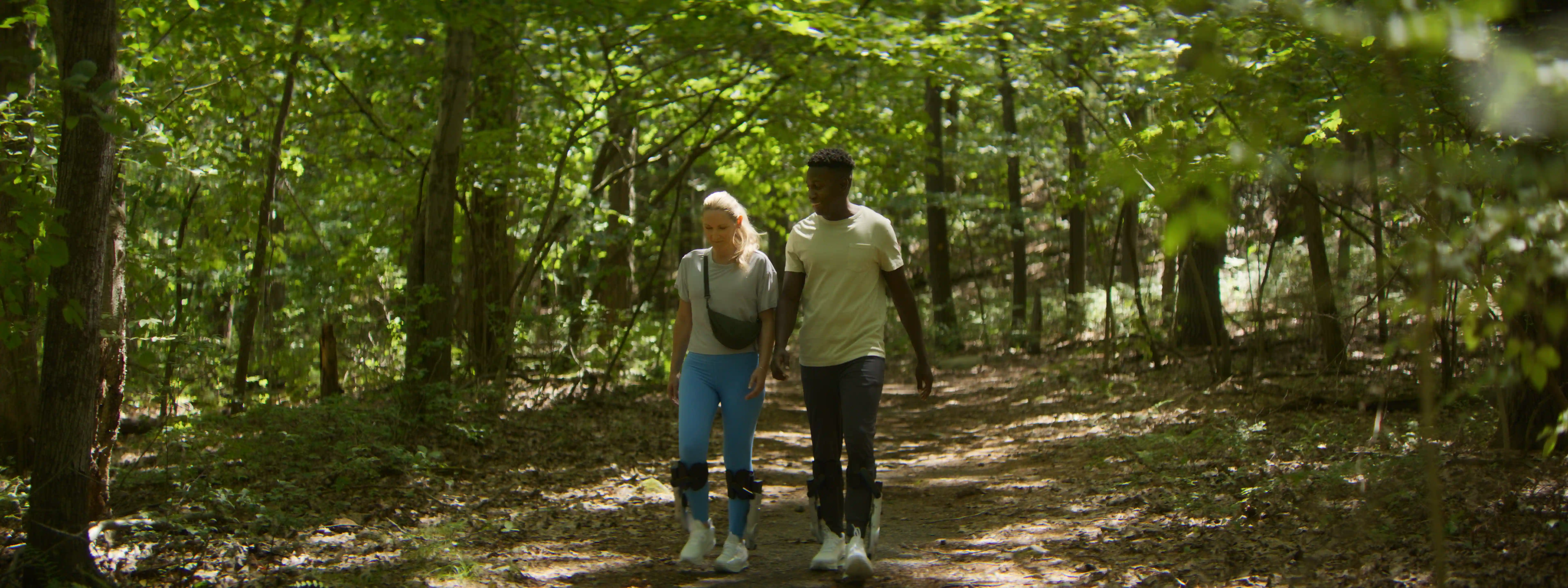 Two people walking together on a tree-lined trail in a natural outdoor setting