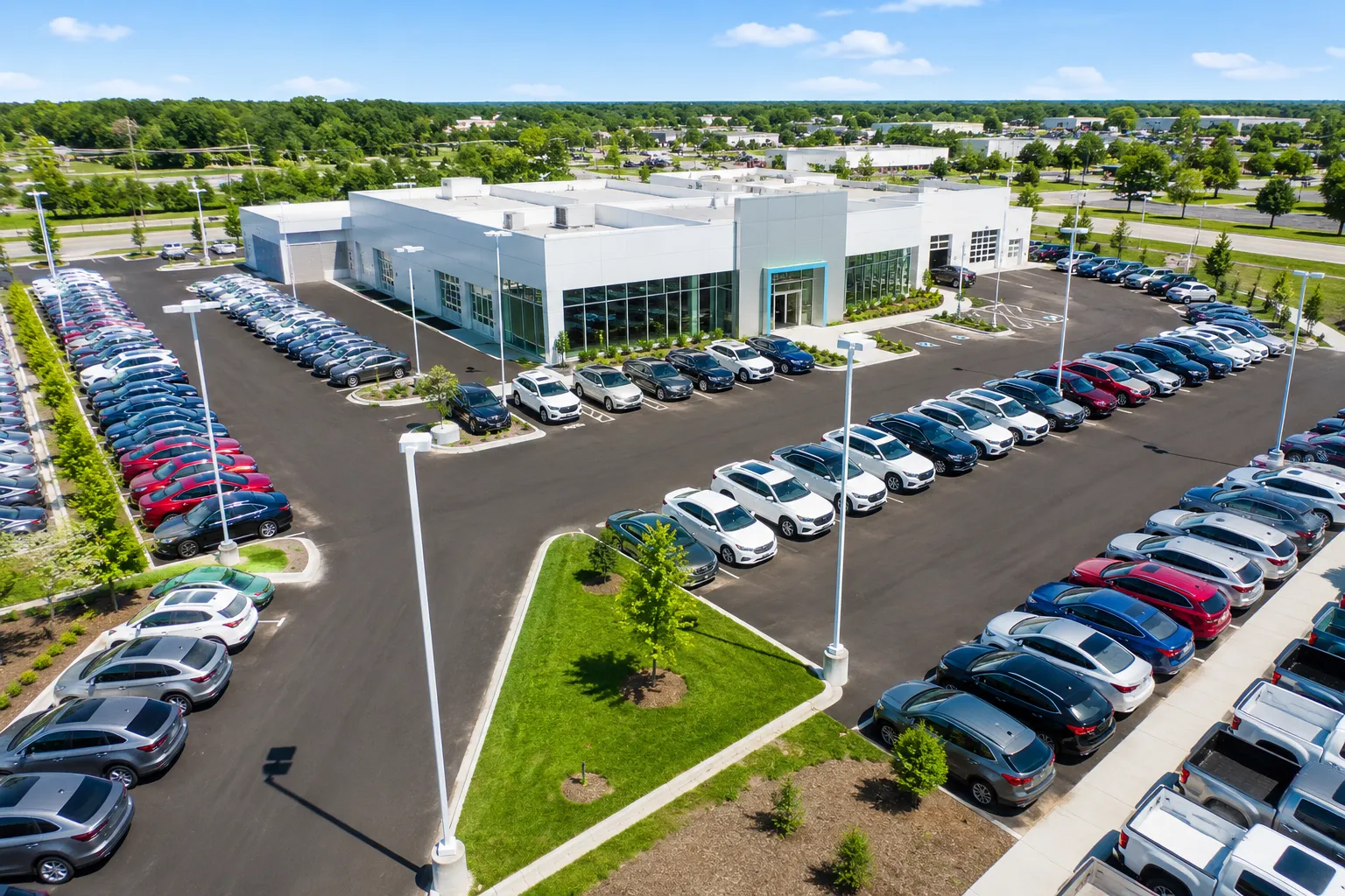 Car salesman showing a couple vehicles in a showroom with cars lined up on both sides.