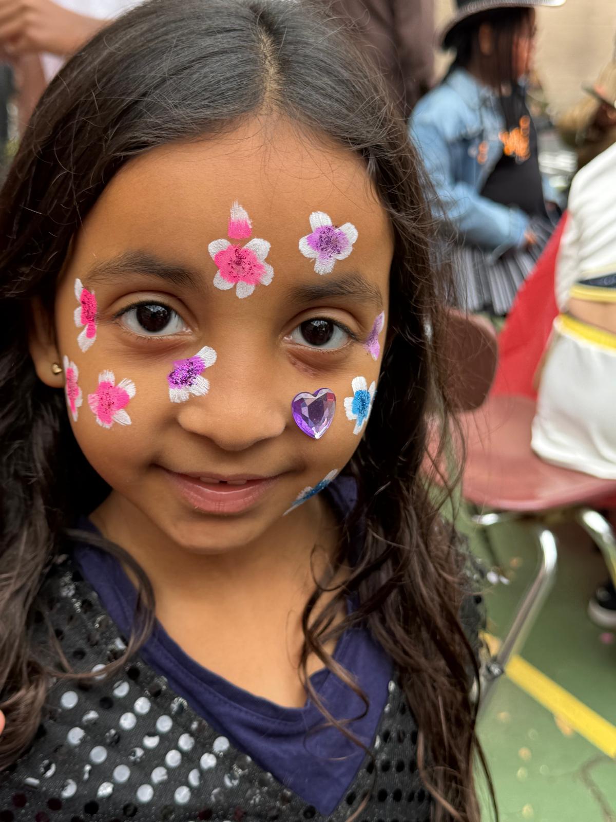 Student smiling with colorful flower face paint at school event