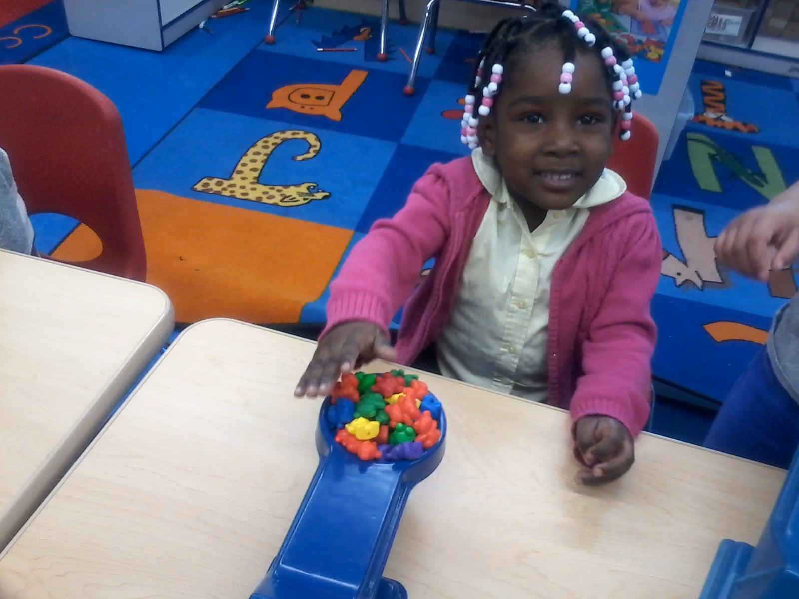 Young girl sorting colorful counting bears at classroom table