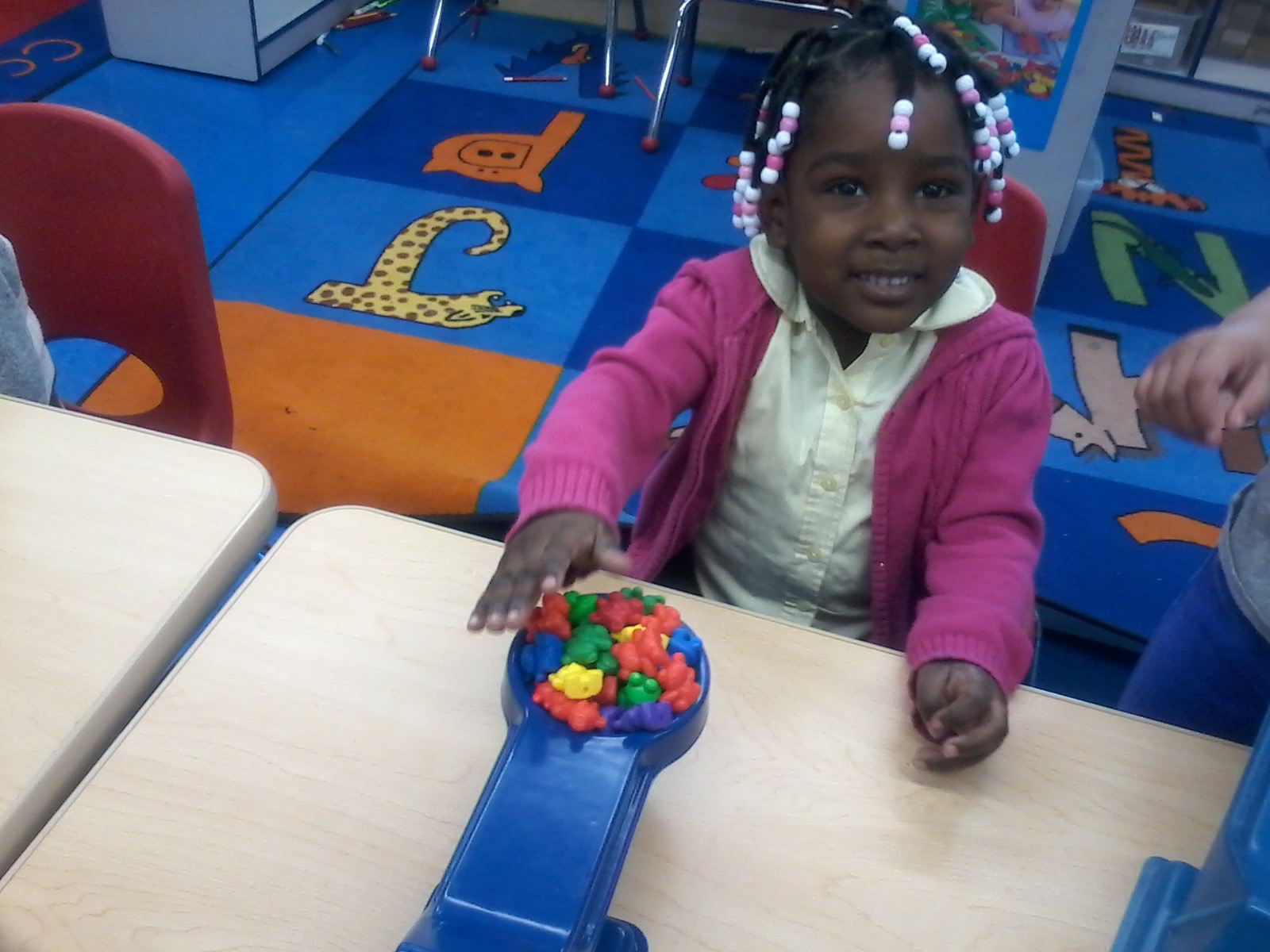 Young girl sorting colorful counting bears at classroom table