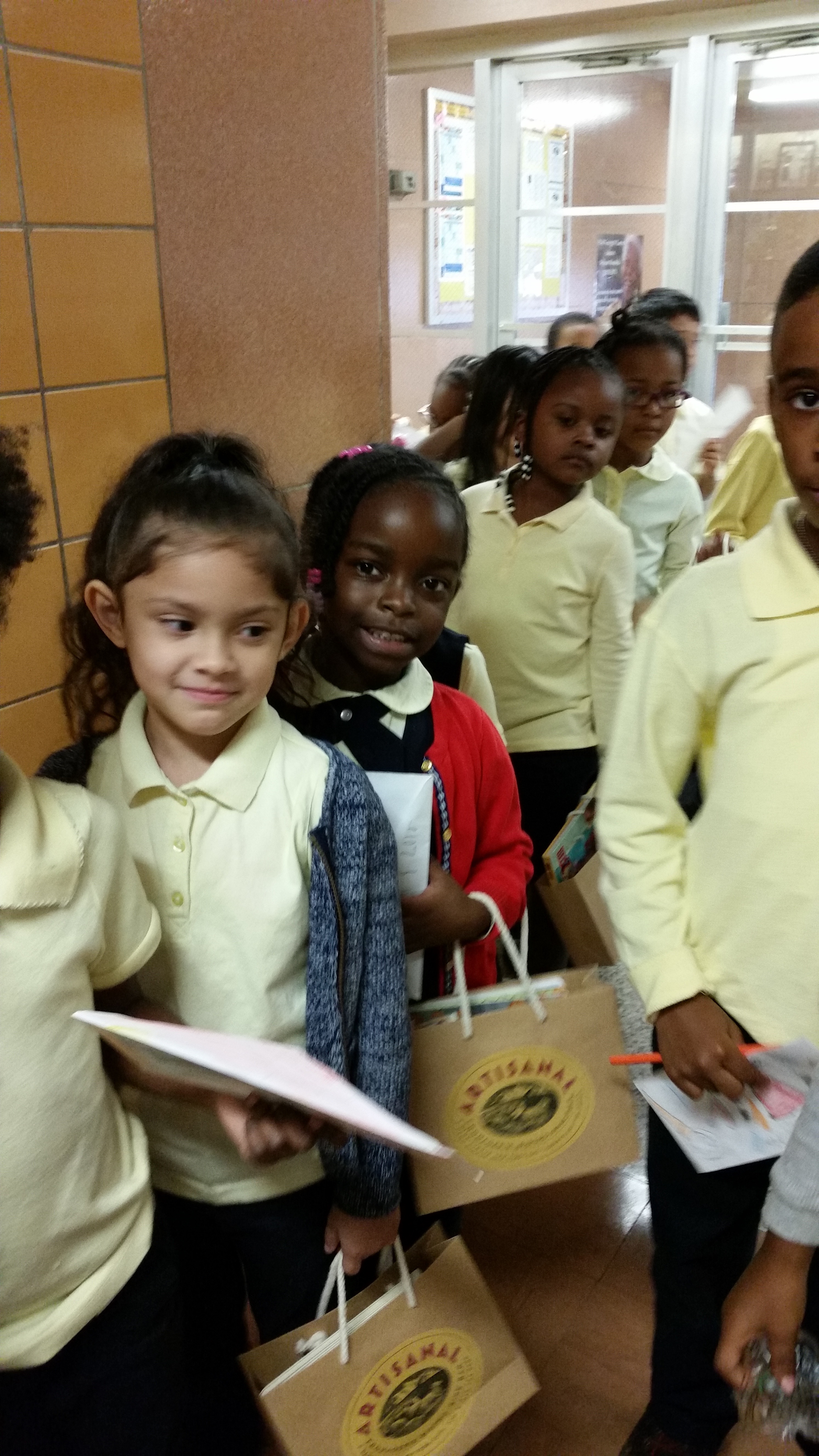 Students in uniform walking in line holding papers and bags