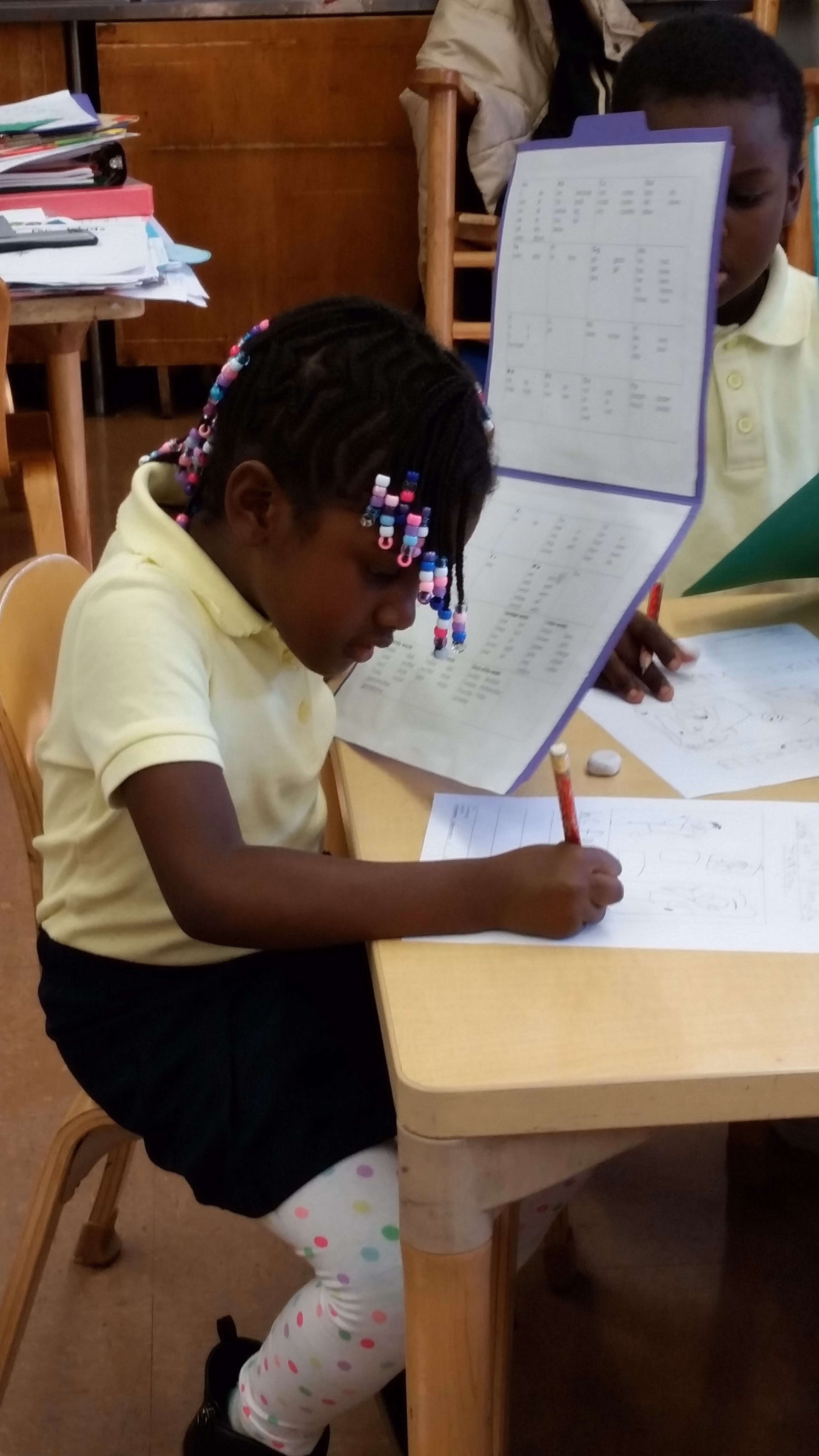 Student writing at desk using a pencil during class work