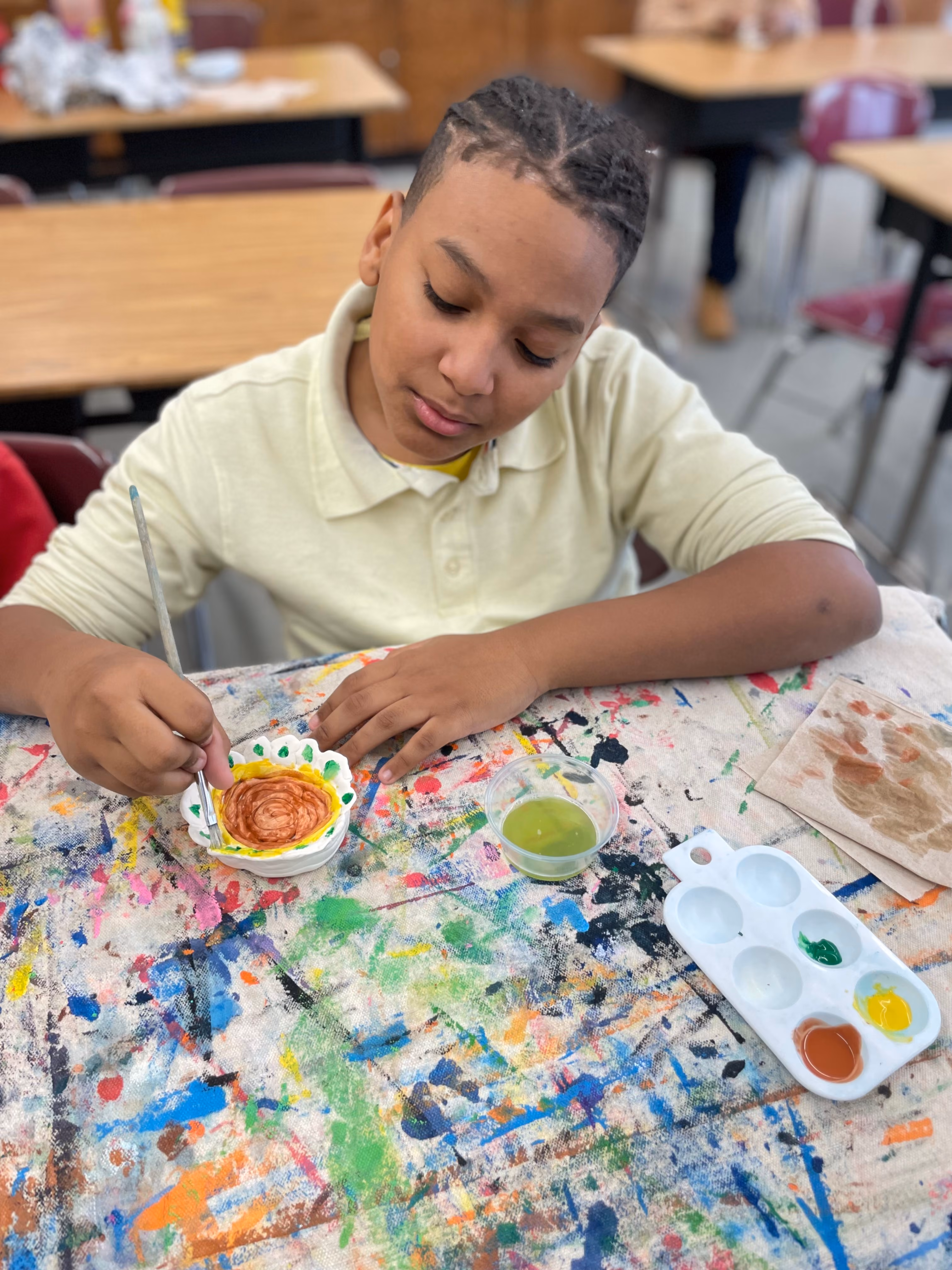 Student painting a ceramic dish during art class