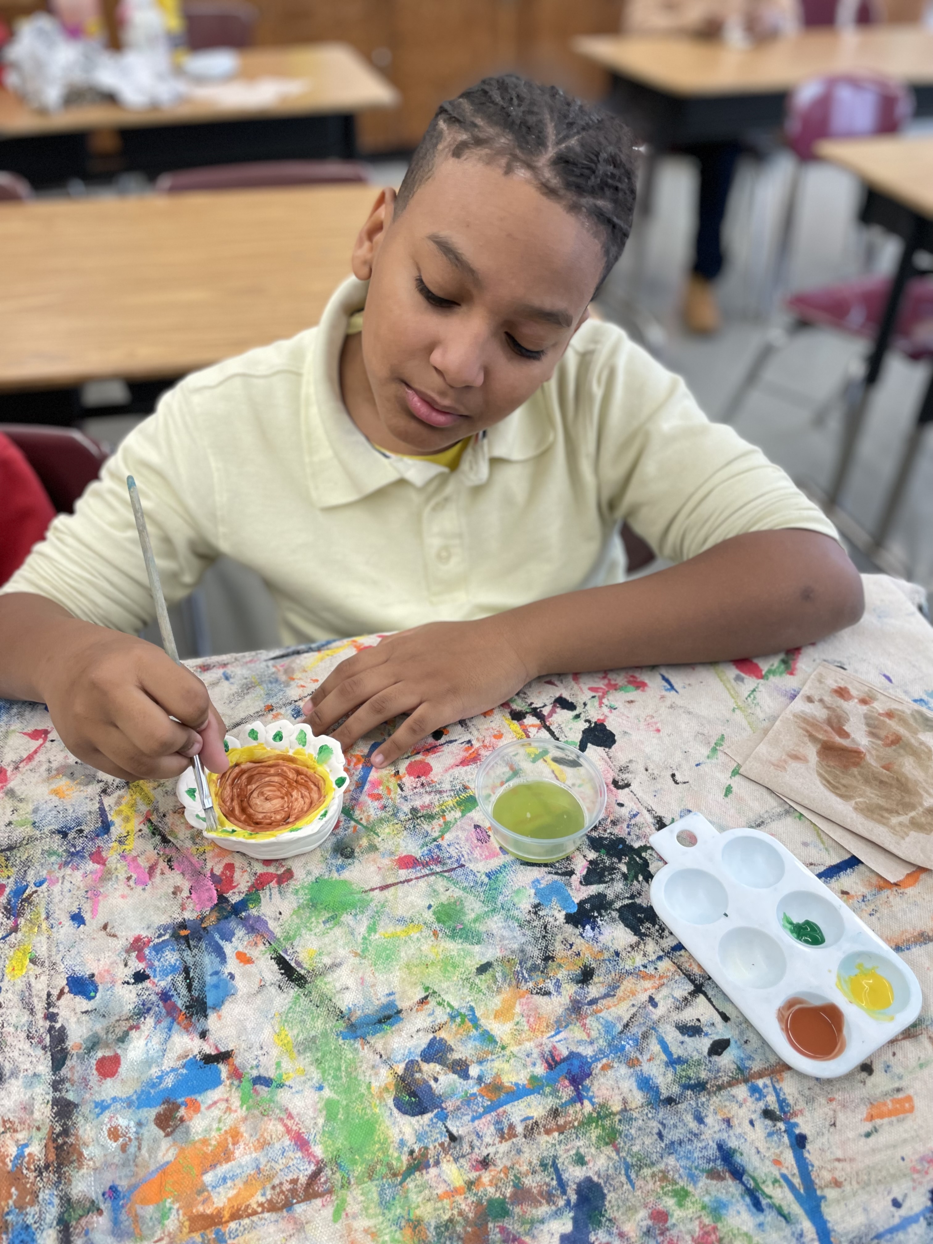 Student painting a ceramic dish during art class