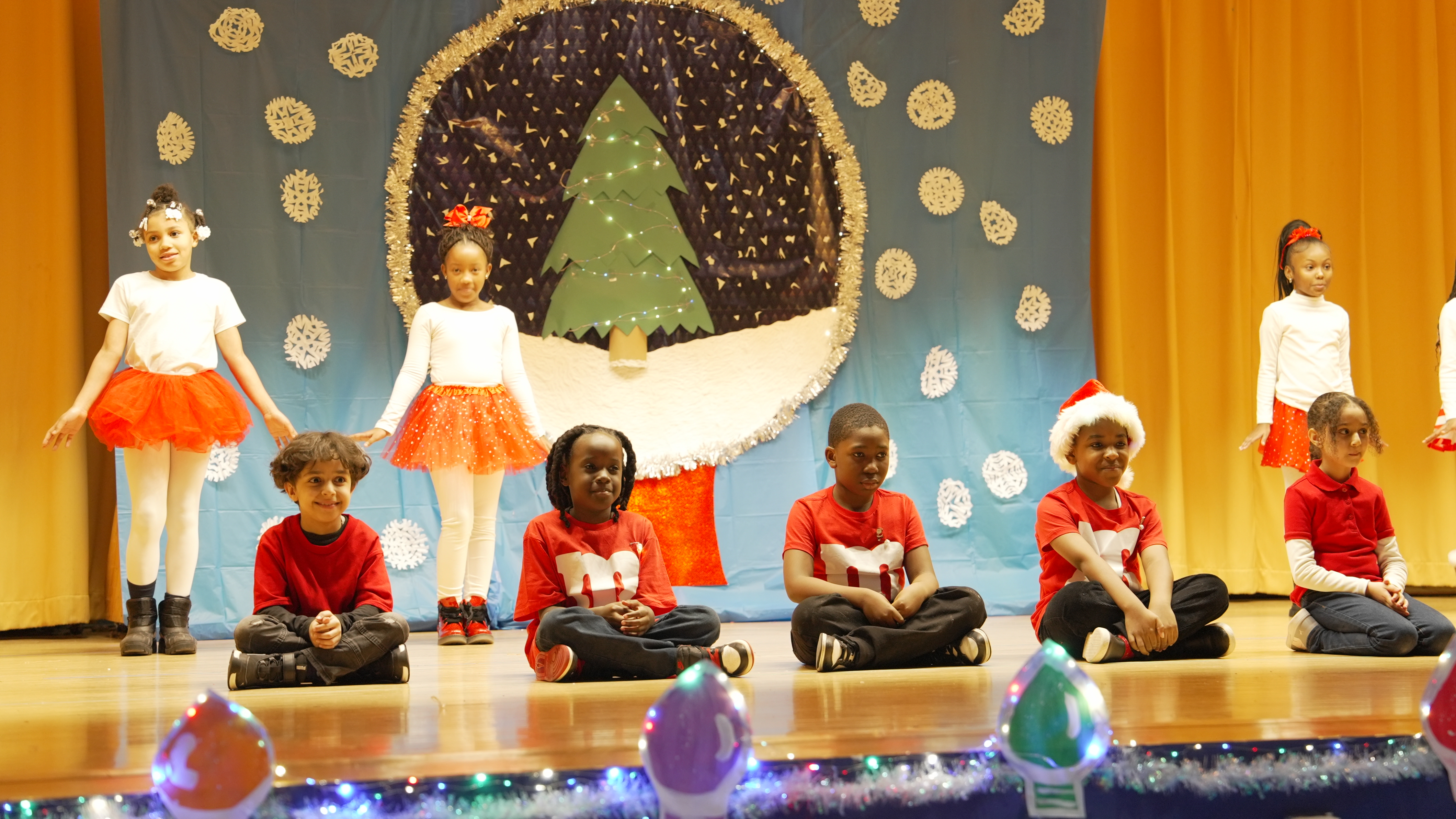 Students performing in a holiday stage show with Christmas backdrop